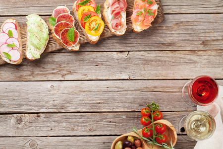 Brushetta or traditional spanish tapas. Appetizers italian antipasti snacks set on wooden board with rose and white wine. Top view and flat lay with space for your textの写真素材