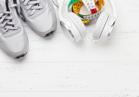 Fitness and healthy life concept. Sneakers, tape measure and headphones on wooden table. Top view with copy space for your textの写真素材