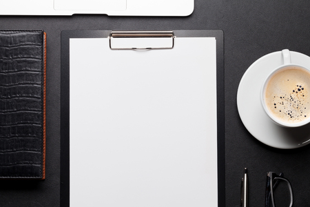 Office workplace table with blank paper page, coffee cup, supplies and laptop. Flat lay. Top view with space for your goalsの写真素材