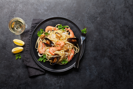 Spaghetti seafood pasta with clams and prawns. White wine glass. Top view with copy space. Flat lay