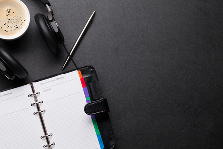 Office desk with notepad, coffee cup and headphones. Top view with copy spaceの写真素材