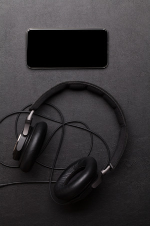 Headphones and smartphone on leather desk table. Top view with copy spaceの写真素材