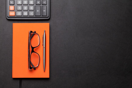 Office workplace table with calculator, supplies and glasses. Flat lay. Top view with space for your goalsの写真素材