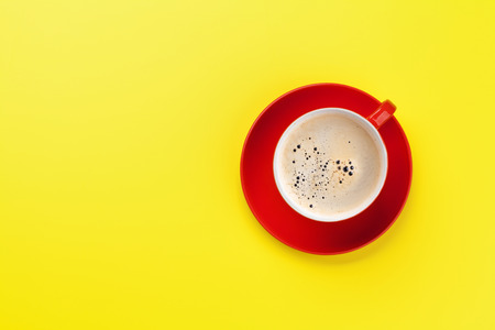 Red coffee cup over yellow background. Top view flat lay with copy spaceの写真素材
