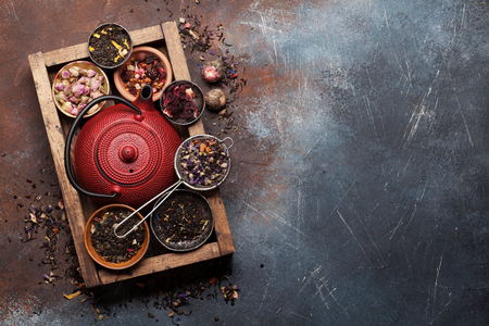 Set of different herbal and fruit dry teas on stone table. Top view flat lay with copy space