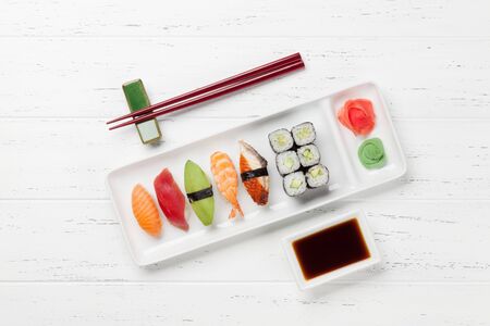 Japanese sushi set. Sashimi, maki rolls. On plate over white wooden background with space for your textの写真素材