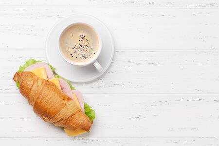 Coffee and croissant sandwich on wooden table. French breakfast. Top view flat lay with copy space for your textの写真素材