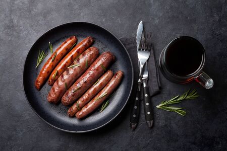Grilled sausages with rosemary herbs and glass of dark beer. Top viewの写真素材