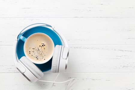 Headphones and coffee cup on wooden desk table. Music concept. Top view with copy spaceの写真素材
