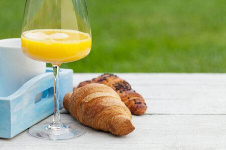 Coffee, orange juice and croissant on sunny garden table. French breakfast. With copy space for your textの写真素材