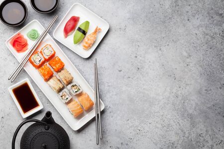Japanese sushi set. Sashimi, maki rolls and green tea. On plate over stone background with space for your text. Top view flat layの写真素材