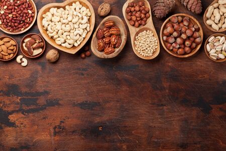 Various nuts selection: peanuts, hazelnuts, chestnuts, walnuts, pistachio and pecans on wooden table. Top view with space for your textの写真素材