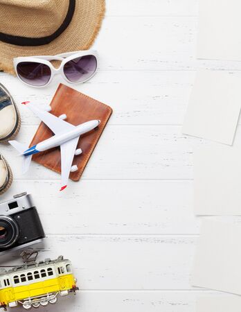 Travel vacation background concept with hat, camera, passport, car, tram, airplane toys and photo frames on wooden backdrop. Top view with copy space. Flat layの写真素材