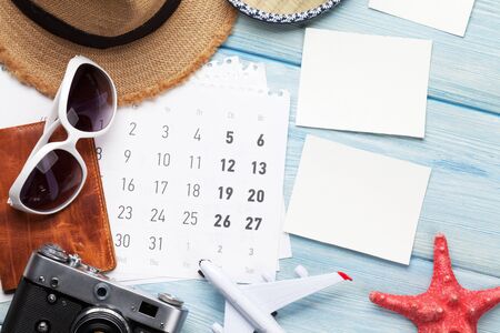 Travel vacation background concept with sun hat, camera, passport, airplane toy and photo frames on wooden backdrop. Top view with copy space. Flat layの写真素材
