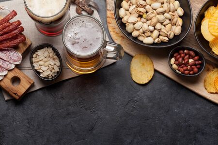 Draft beer and snacks on stone background. Nuts, chips, sausages and shrimps. Flat lay. Top view with copy spaceの写真素材