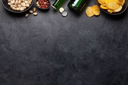Draft beer and snacks on stone background. Nuts, chips, sausages. Flat lay. Top view with copy spaceの写真素材