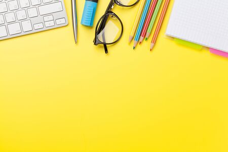 Office yellow workplace backdrop with supplies and computer. Flat lay. Top view with copy space for...