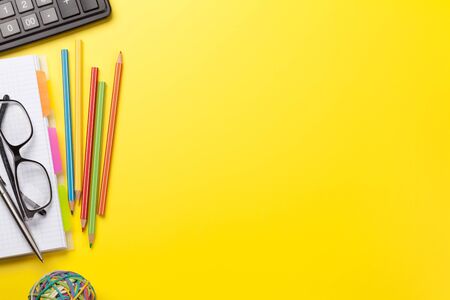 Office yellow workplace backdrop with supplies and glasses. Flat lay. Top view with copy space