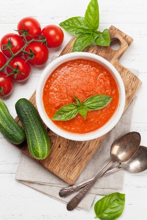 Cold gazpacho soup with ripe tomatoes, cucumber and basil on wooden table. Top view flat layの写真素材