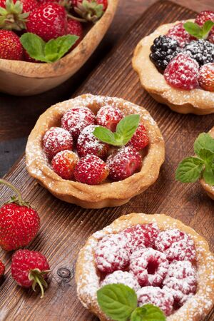 Set of sweet cakes with berries on wooden board. Strawberry, raspberry and blackberryの写真素材