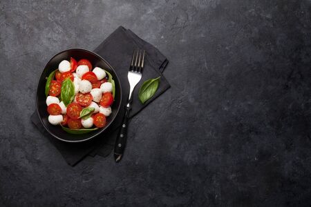 Fresh classic caprese salad with cherry tomatoes, mozzarella, basil leaves and condiment. Flat lay. Top view with copy spaceの写真素材
