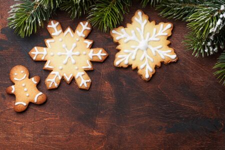 Christmas gingerbread cookies and xmas fir tree branch over wooden backdrop. Top view with space for...