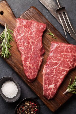 Raw marbled beef steak on wooden board. Spices, utensils. Top view flat layの写真素材