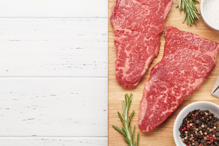 Raw marbled beef steak on wooden board. Top view flat lay with copy space