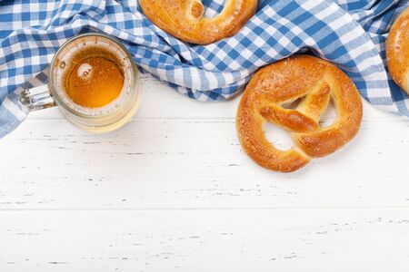 Oktoberfest food backdrop. Pretzels and lager beer mug on white wooden background. Top view with...