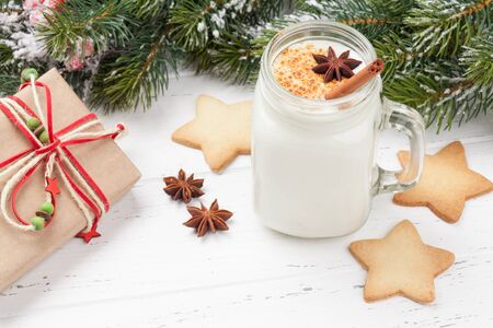 Eggnog. Traditional christmas cocktail and gingerbread cookies. With xmas gift boxes on wooden tableの写真素材