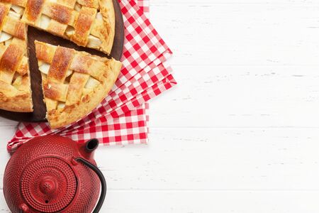 Traditional apple pie on wooden board and tea pot. Top view with copy spaceの写真素材