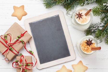Eggnog. Traditional christmas cocktail and gingerbread cookies on wooden table. Flat lay. Top view with chalkboard for your greetingsの写真素材