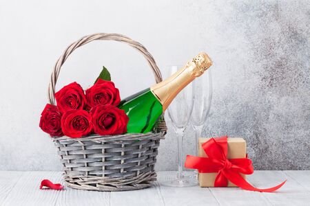 Valentine's day greeting card with red rose flowers bouquet and champagne in basket. With space for your greetingsの写真素材