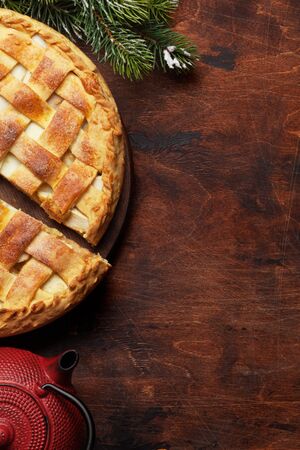 Christmas holiday greeting card with apple pie and fir tree. On wooden table with copy space. Top view flat layの写真素材