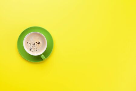 Green coffee cup over yellow background. Top view flat lay with copy spaceの写真素材