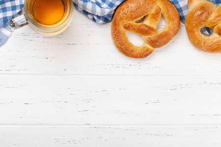 Oktoberfest food backdrop. Pretzels and lager beer mug on white wooden background. Top view with...