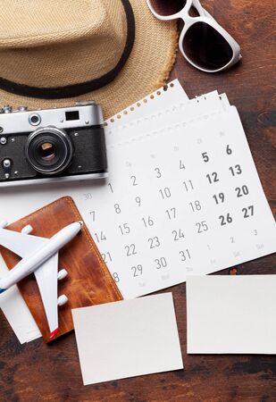 Travel vacation concept with sun hat, camera, passport, airplane toy and photo frames on wooden backdrop. Top view. Flat layの写真素材