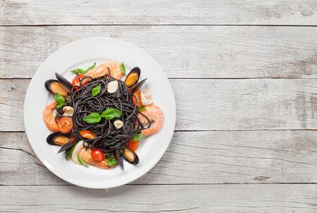 Black spaghetti pasta with seafood, tomatoes and basil. Top view flat lay with copy spaceの写真素材