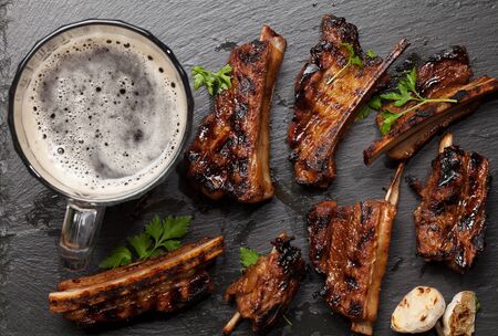Barbecue beef ribs with bbq sauce sliced on a stone board with beer mug. Top view flat layの写真素材