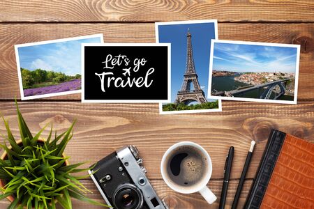 Camera, travel photos and supplies on office wooden desk table. Top view with copy spaceの写真素材