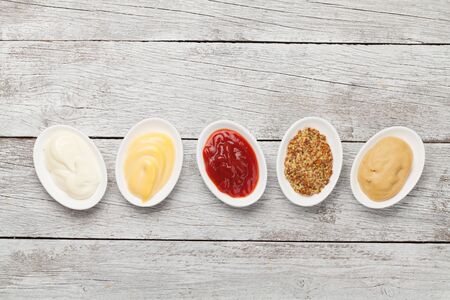 Set of various sauces. Popular sauces in bowls - ketchup, mustard, mayonnaise on white wooden table. Top view with copy space. Flat layの写真素材