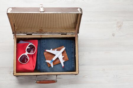 Suitcase with clothes and travel accessories. Tourist and vacation things on wooden background with space for your text. Top view flat layの写真素材