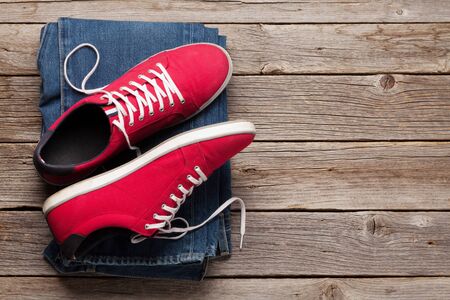 Clothing and accessories. Sneakers and jeans. Urban outfit for everyday or travel vacation on wooden background with copy space. Top view flat layの写真素材