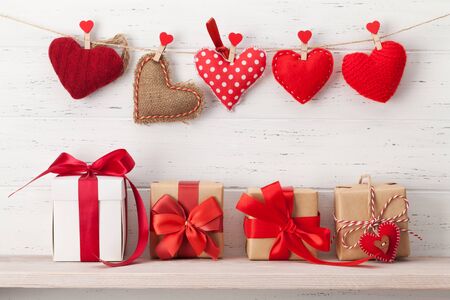 Valentines day greeting card with handmade hearts and various gift boxes in front of wooden wall with copy space for your greetingsの販売画像
