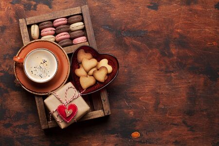 Valentines day greeting card with coffee cup, cookies and gift box on wooden background. Top view flat lay with space for your greetingsの写真素材