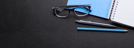 Office desk with notepad and supplies. Top view with space for your text. Wide flat lay