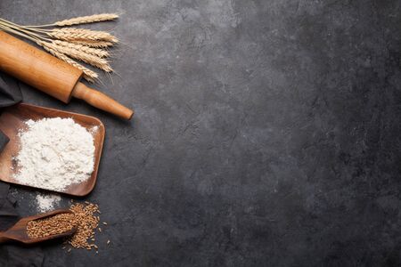Various bread ingredients. Wheat, flour and cooking utensils on stone table. Top view flat lay with...
