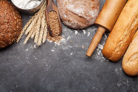 Various bread with wheat, flour and utensils on stone table. Homemade cooking concept. Top view flat...