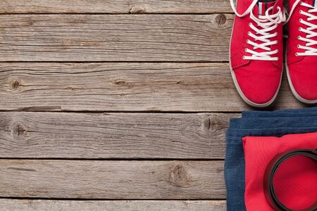 Clothing and accessories. Sneakers, shirt and jeans. Urban outfit for everyday or travel vacation on wooden background with copy space. Top view flat layの写真素材