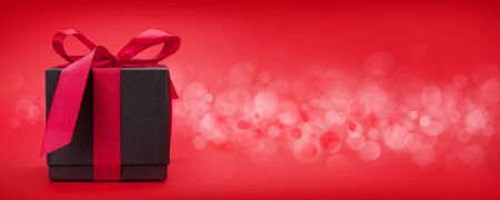 Valentines day greeting card with gift box in front of red background with space for your greetings